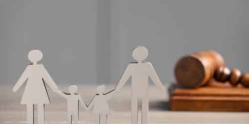 Paper figures of parents with children and gavel on wooden table